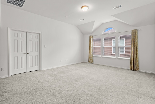 carpeted empty room featuring vaulted ceiling