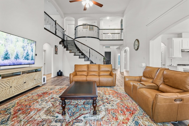 living room with a towering ceiling, ceiling fan, and light hardwood / wood-style flooring