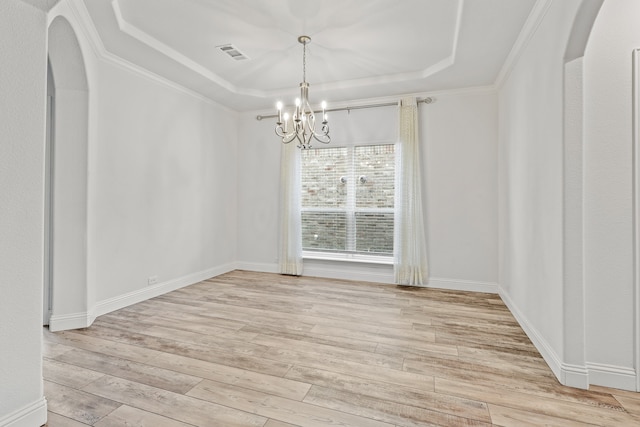 spare room with crown molding, a tray ceiling, light hardwood / wood-style flooring, and a notable chandelier