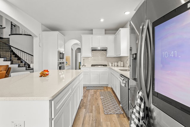 kitchen featuring light hardwood / wood-style flooring, stainless steel appliances, white cabinetry, and decorative backsplash