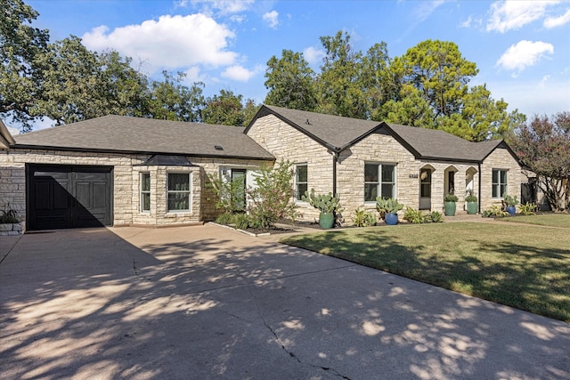 single story home featuring roof with shingles, a front yard, driveway, and stone siding