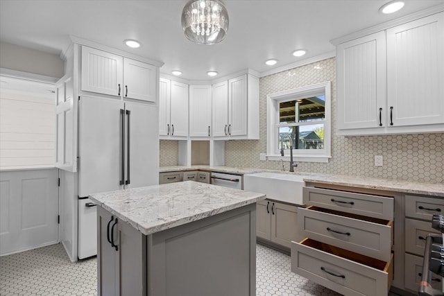 kitchen with high end refrigerator, decorative light fixtures, a kitchen island, light stone counters, and white cabinetry