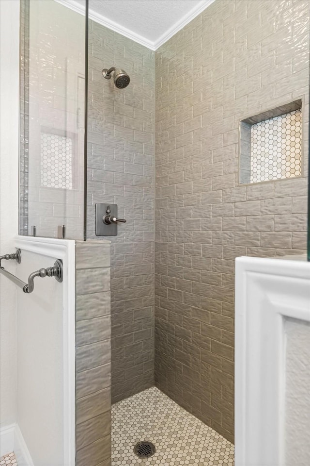 bathroom with a tile shower and ornamental molding