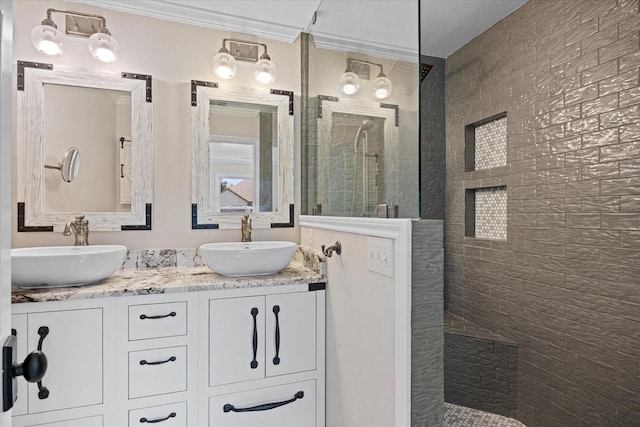 bathroom featuring a tile shower, vanity, and crown molding