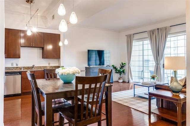 dining area featuring crown molding, sink, and dark wood-type flooring