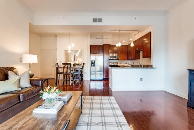 living room featuring rail lighting, dark wood-type flooring, and ornamental molding