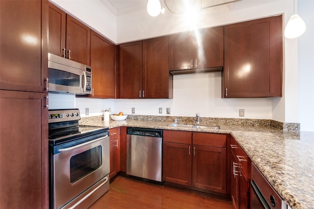 kitchen with sink, dark hardwood / wood-style floors, light stone countertops, appliances with stainless steel finishes, and decorative light fixtures