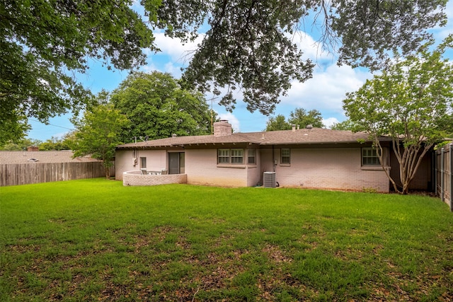 rear view of property featuring cooling unit and a lawn