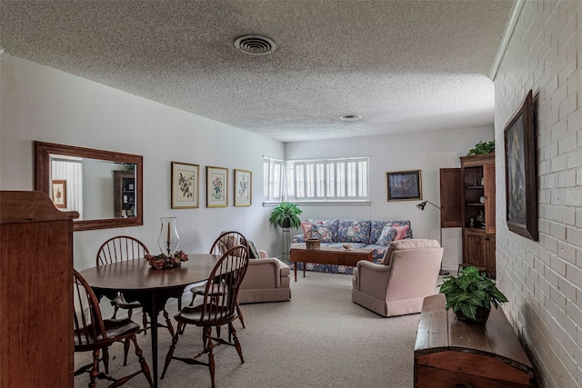 dining area featuring carpet floors, a textured ceiling, and brick wall