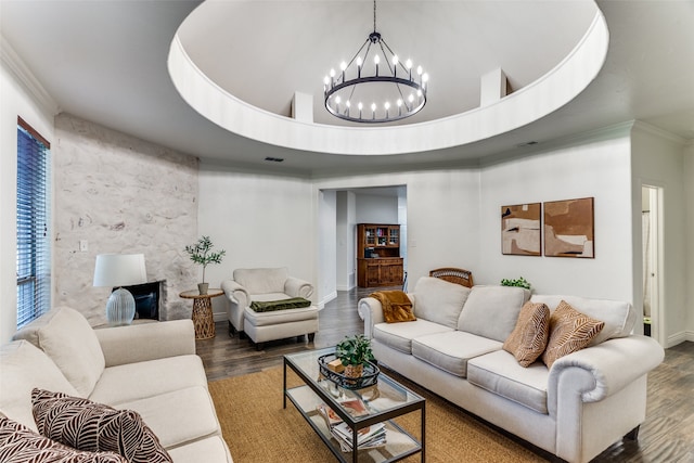 living room with dark hardwood / wood-style flooring, a high ceiling, a tray ceiling, ornamental molding, and a chandelier