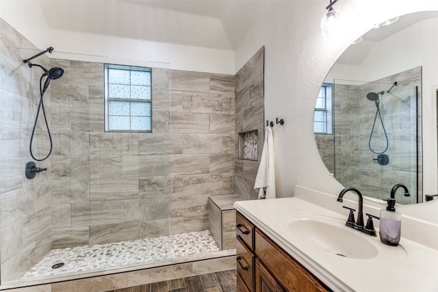 bathroom with wood-type flooring, tiled shower, and vanity