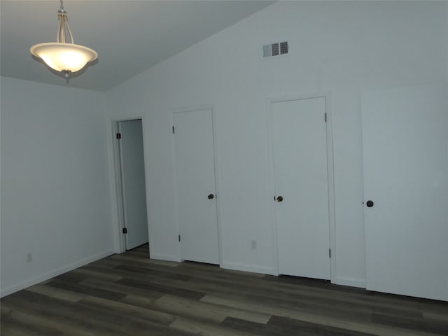 unfurnished bedroom with multiple closets, lofted ceiling, and dark wood-type flooring