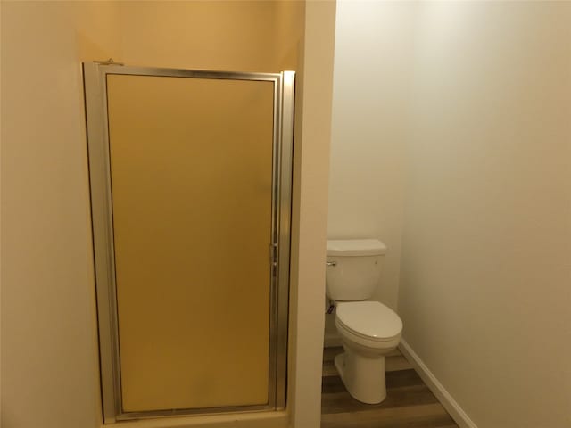 bathroom featuring walk in shower, hardwood / wood-style floors, and toilet