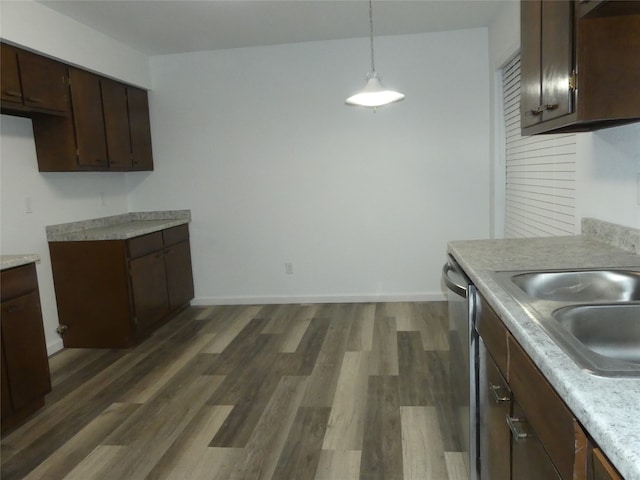 kitchen featuring dark brown cabinetry, pendant lighting, sink, dishwasher, and dark hardwood / wood-style floors