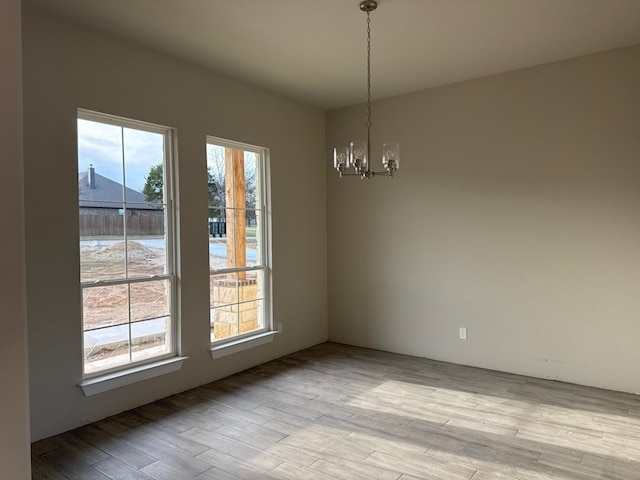 unfurnished dining area featuring light wood-type flooring and an inviting chandelier