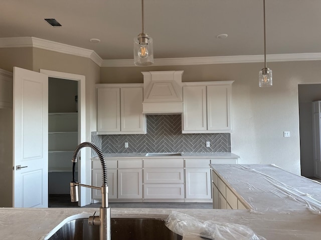 kitchen with decorative backsplash, white cabinetry, hanging light fixtures, and custom exhaust hood