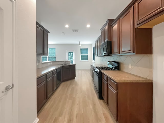 kitchen featuring decorative backsplash, black appliances, light hardwood / wood-style floors, and sink