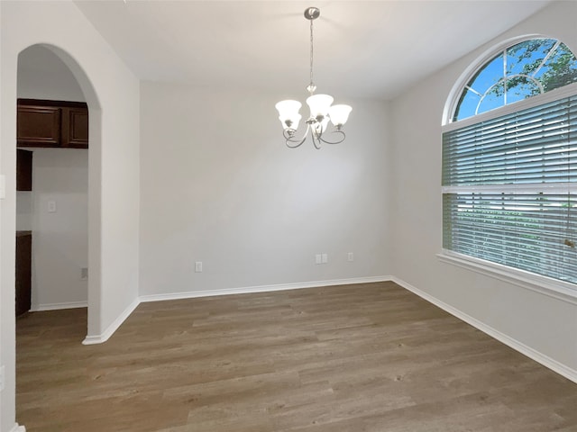 unfurnished room featuring an inviting chandelier and hardwood / wood-style flooring