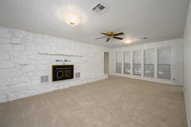 unfurnished living room with a textured ceiling, carpet, a fireplace, and ceiling fan