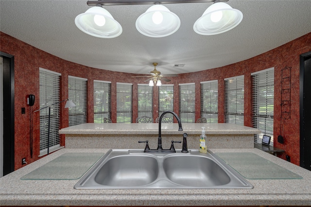 kitchen with a textured ceiling, ceiling fan, and sink