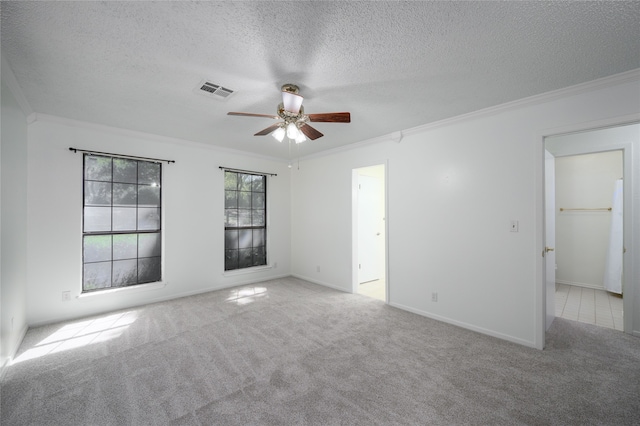 spare room featuring ceiling fan, light colored carpet, a textured ceiling, and ornamental molding