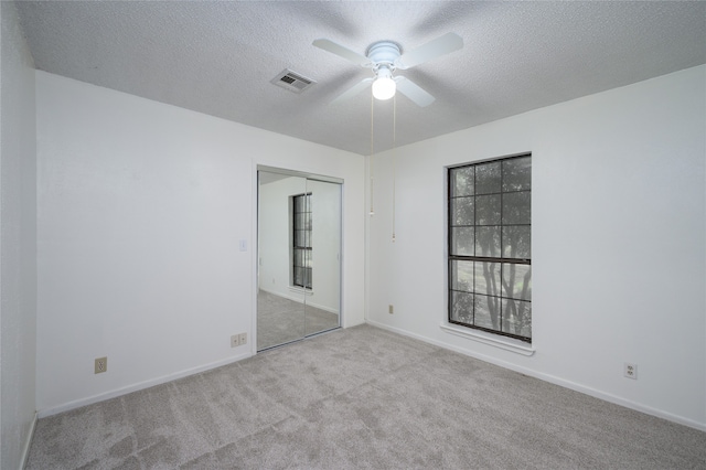 carpeted empty room with ceiling fan and a textured ceiling