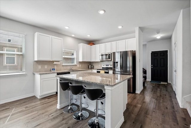 kitchen with a kitchen breakfast bar, white cabinetry, appliances with stainless steel finishes, and a kitchen island