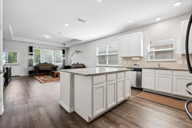 kitchen with white cabinetry, a kitchen island, decorative backsplash, dark hardwood / wood-style flooring, and stainless steel dishwasher