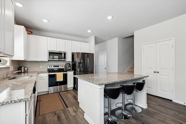 kitchen with sink, a kitchen island, dark wood-type flooring, white cabinetry, and appliances with stainless steel finishes