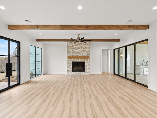 unfurnished living room with a fireplace, beam ceiling, light hardwood / wood-style flooring, and ceiling fan