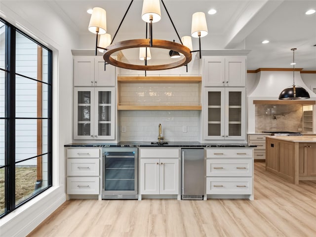 kitchen featuring white cabinets, hanging light fixtures, wine cooler, decorative backsplash, and light hardwood / wood-style floors