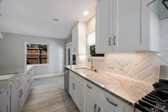 kitchen featuring light stone countertops, white cabinetry, light hardwood / wood-style flooring, and range