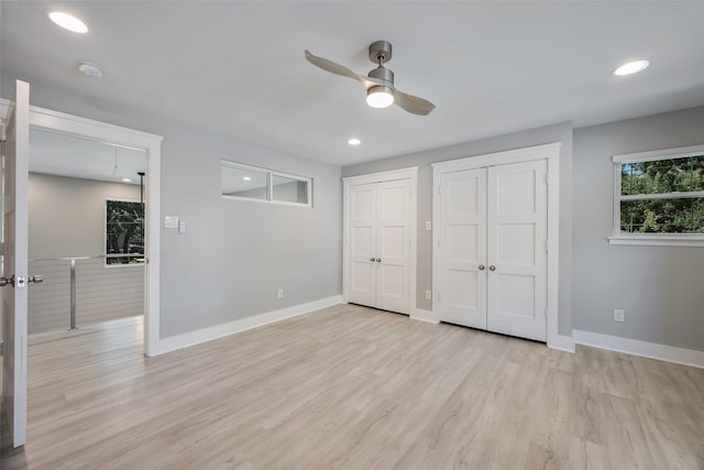 unfurnished bedroom featuring ceiling fan, light wood-type flooring, and two closets