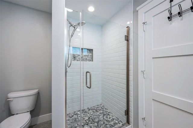 bathroom with a shower with door and toilet