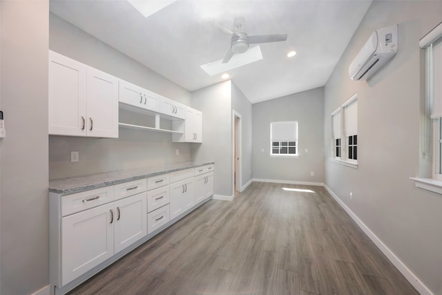 kitchen with an AC wall unit, white cabinetry, ceiling fan, and dark hardwood / wood-style flooring