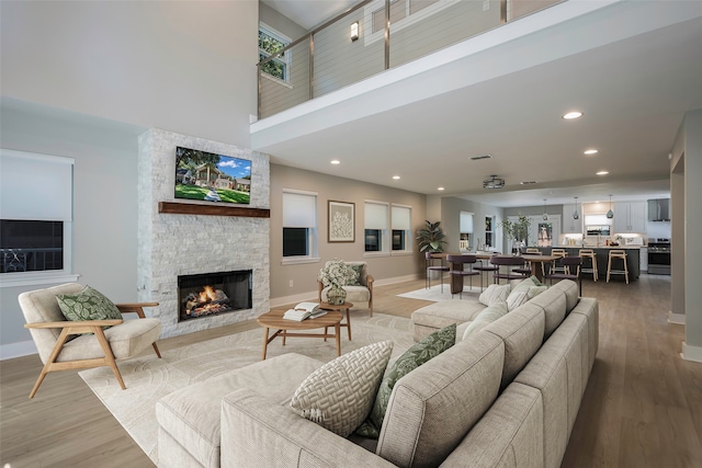 living room with hardwood / wood-style flooring, a fireplace, and a towering ceiling