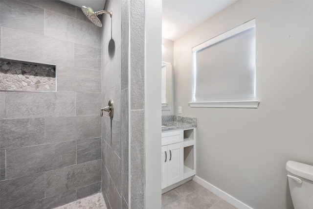 bathroom featuring a tile shower, vanity, tile patterned flooring, and toilet