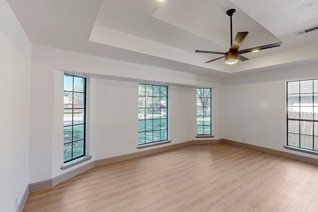 unfurnished room with a healthy amount of sunlight, light hardwood / wood-style floors, and ceiling fan