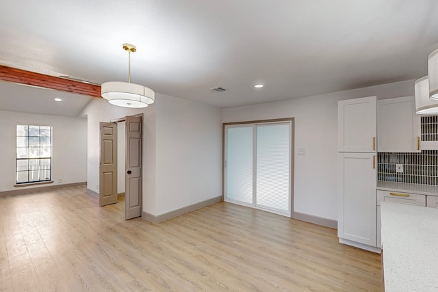 kitchen with pendant lighting, white cabinetry, lofted ceiling with beams, light wood-type flooring, and decorative backsplash