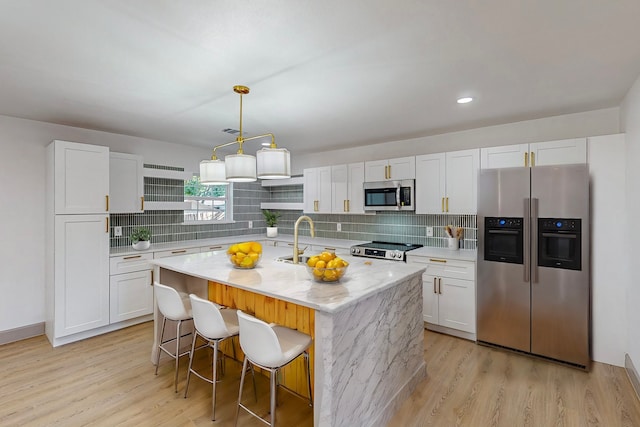 kitchen featuring appliances with stainless steel finishes, a center island with sink, and white cabinetry