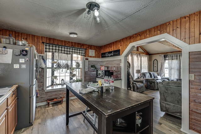 kitchen with light hardwood / wood-style flooring, wood walls, and vaulted ceiling