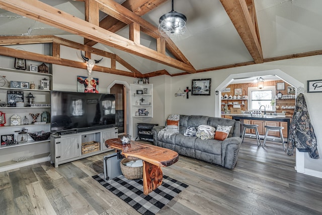 living room with ceiling fan, vaulted ceiling with beams, hardwood / wood-style flooring, and sink