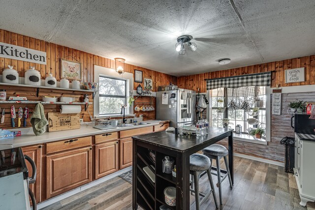 kitchen with a sink, stainless steel appliances, a healthy amount of sunlight, and wooden walls