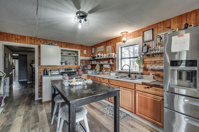 kitchen featuring wood walls, sink, white cabinetry, appliances with stainless steel finishes, and hardwood / wood-style floors