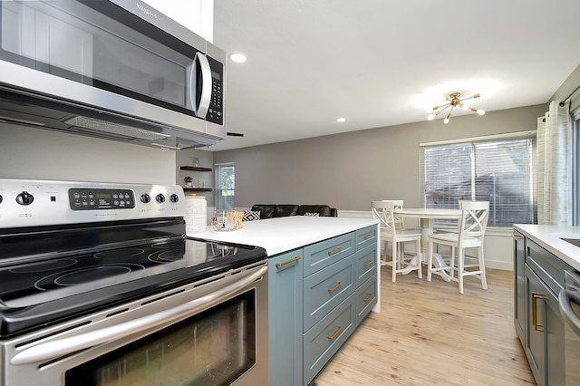 kitchen featuring an inviting chandelier, stainless steel appliances, light wood-type flooring, and a wealth of natural light