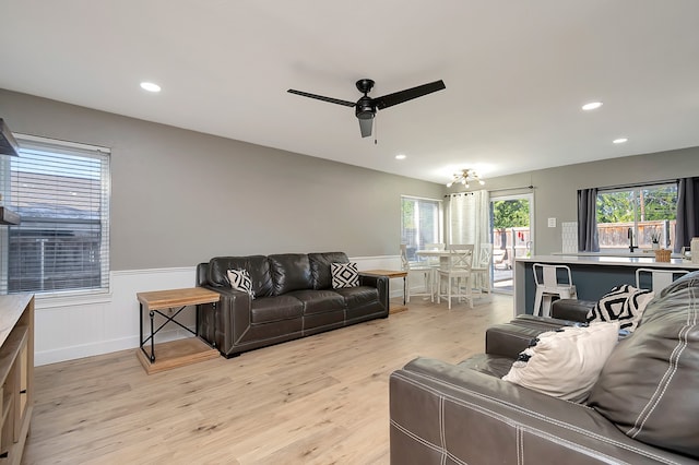 living room with light hardwood / wood-style floors, ceiling fan, and a wealth of natural light