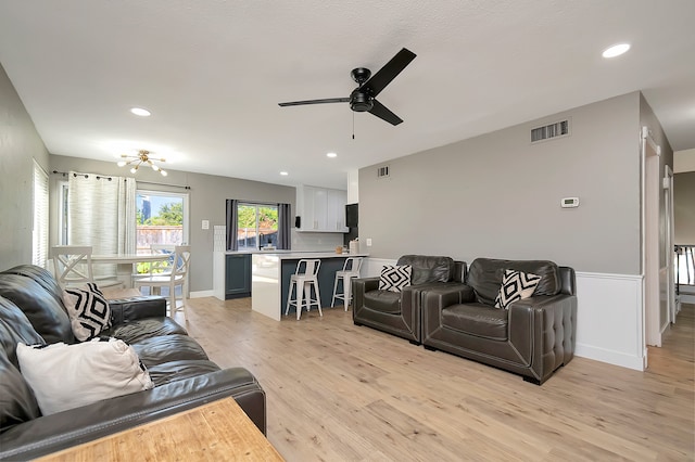 living room featuring ceiling fan, light hardwood / wood-style flooring, and sink