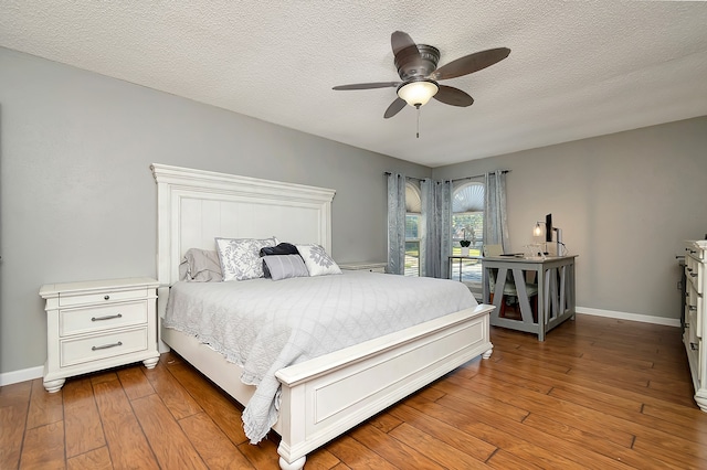 bedroom featuring wood-type flooring, a textured ceiling, and ceiling fan