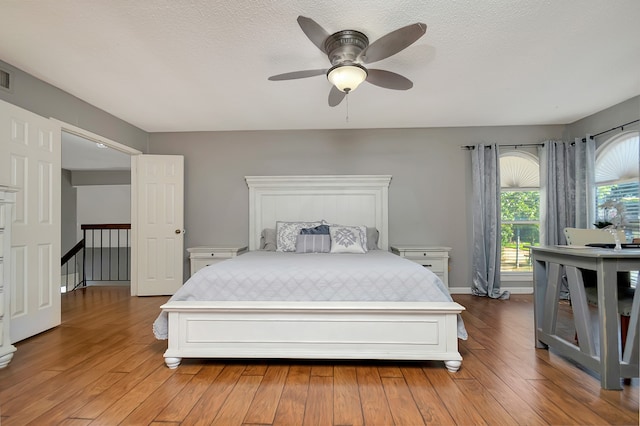 bedroom with light hardwood / wood-style flooring, ceiling fan, and a textured ceiling