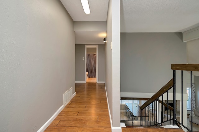 hall featuring wood-type flooring and a textured ceiling